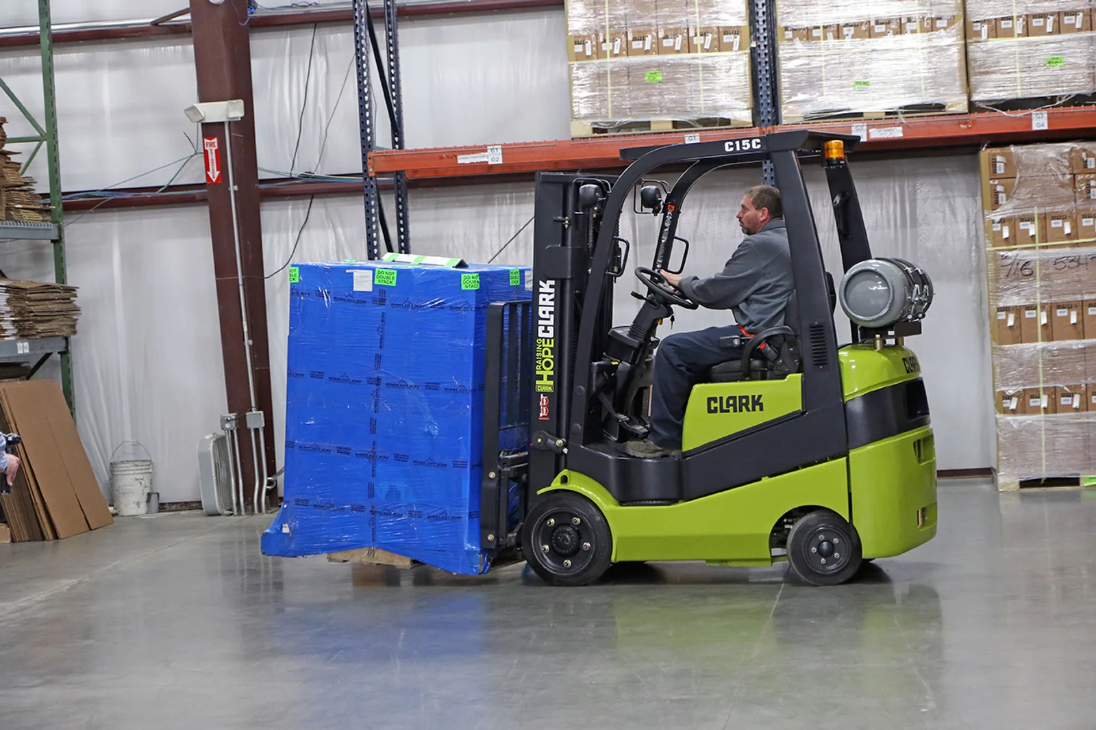 New Clark C15C forklift carrying a wrapped pallet past pallet racking in a Delaware warehouse